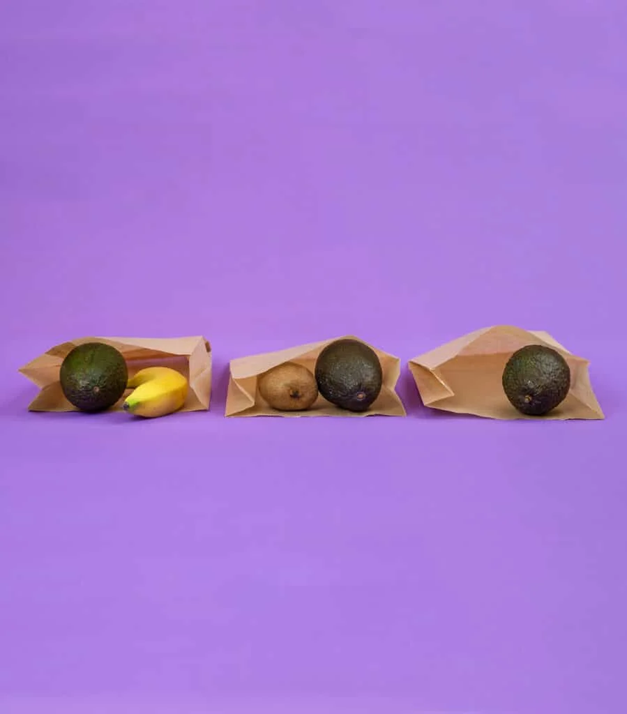Three paper bags containing avocados and bananas