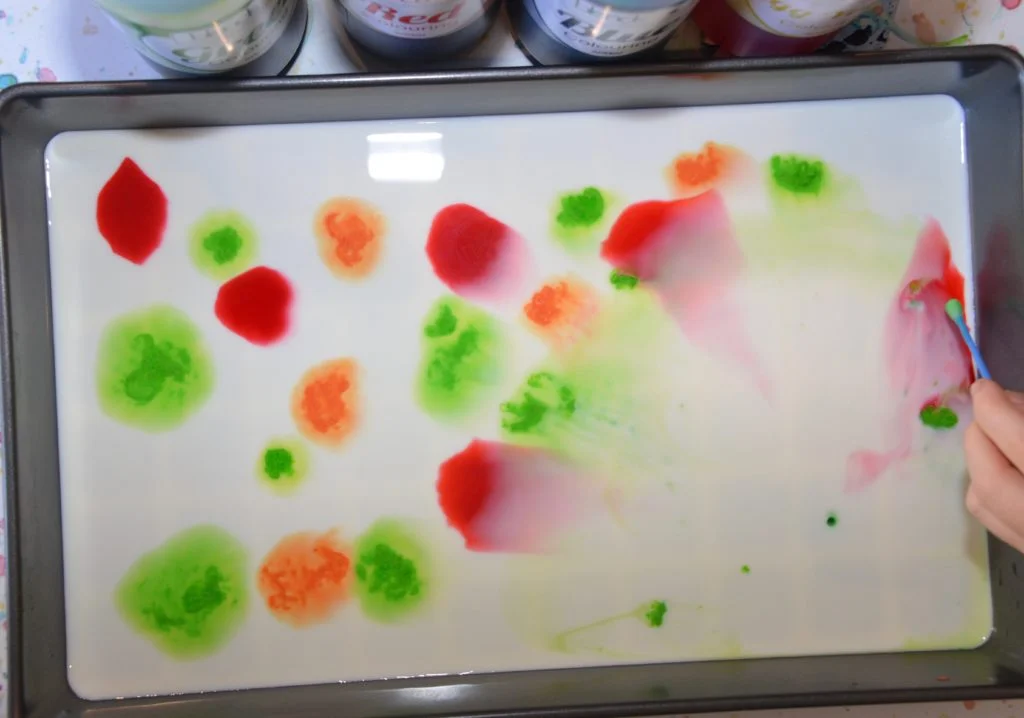Milk and food coloring in a shallow tray for a magic milk science experiment.
